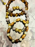 M.C’s set of three stretch bracelets featuring amber glass, lavender stones, wood-grain beads, and cream pearls.
