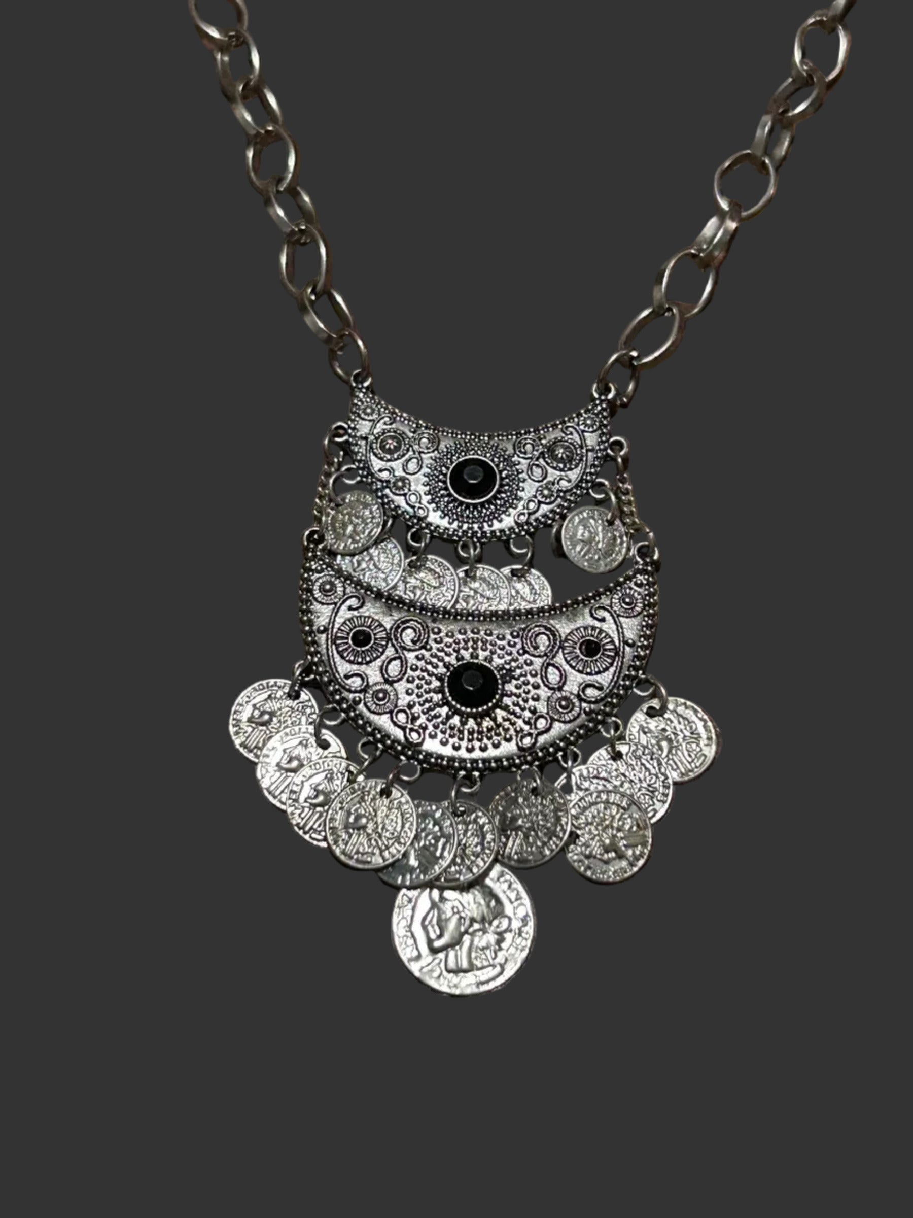 M.C’s bohemian silver-tone crescent moon statement necklace with engraved coin charms and dark stone accents.
