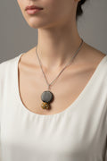 M.C’s decorative pendant necklace featuring a matte dark grey disc and a mustard beaded charm on a silver-tone chain.