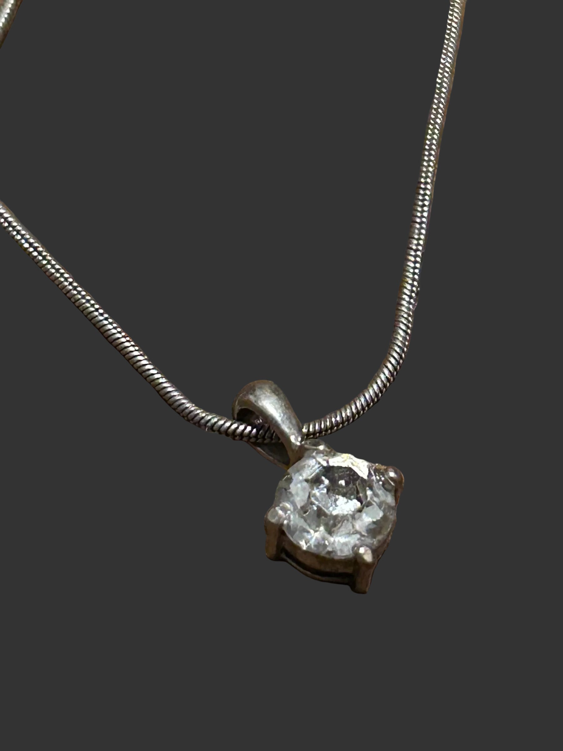 M.C’s solitaire pendant necklace featuring a round-cut clear stone in a silver-tone four-prong setting on a snake chain